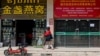 This photo taken on Oct. 8, 2024, shows a woman walking in front Chinese stores in Laos' capital, Vientiane.