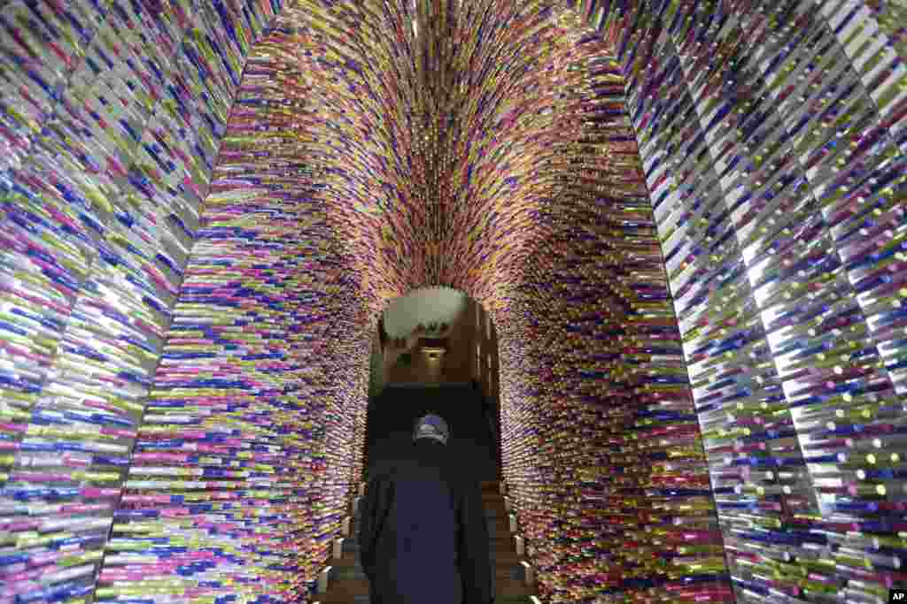 Seorang pria lewat di bawah lorong yang disebut "Transisi", yang dibuat dengan menggunakan paket lipstik, bagian dari Pameran Furniture di Milan, Italia.