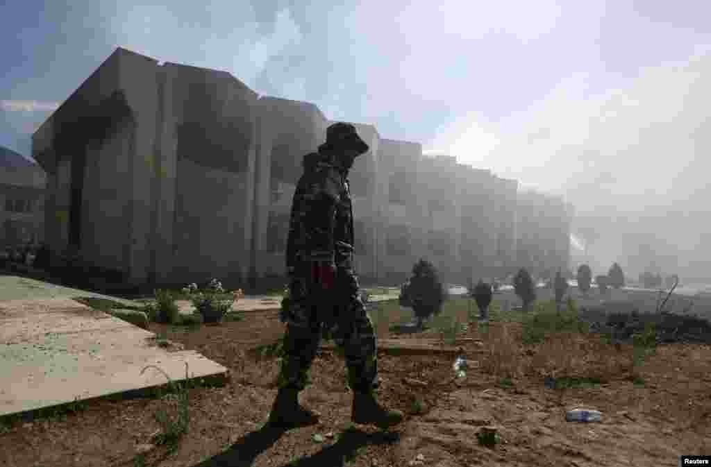 An Afghan security officer walks in front of a government building after an attack by insurgents, Panjshir, Afghanistan, May 29, 2013.