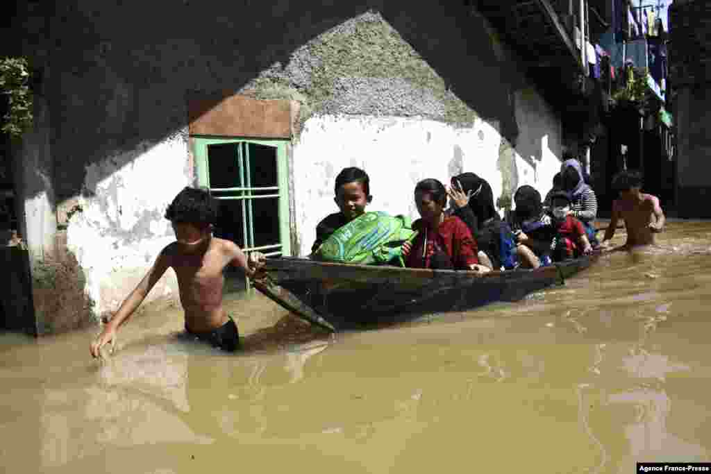 A family evacuates from their flooded home following heavy rain in Bandung, Indonesia.