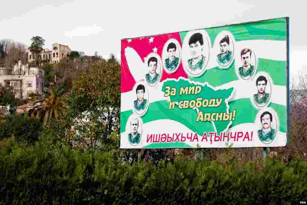Gambar pahlawan-pahlawan perang pada bendera Abkhaz, dengan tulisan dalam bahasa Rusia dan Abkhaz: "Untuk perdamaian dan kebebasan Abkhazia!” (V. Undritz/VOA)