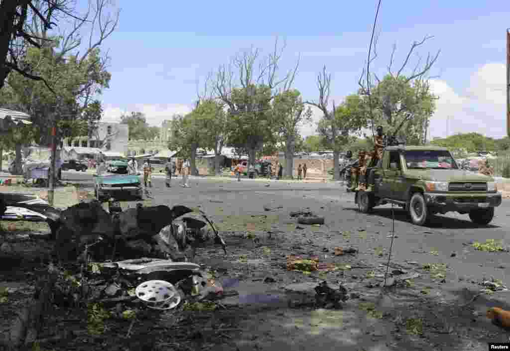 Somali government soldiers drive past the scene of a suicide car bomb attack next to a cafe in the suburbs of Mogadishu, Feb. 27, 2014.