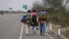 ARCHIVO - Tres migrantes venezolanos caminan en la autopista Panamericana hacia Lima desde Ecuador, el 26 de agosto de 2018.