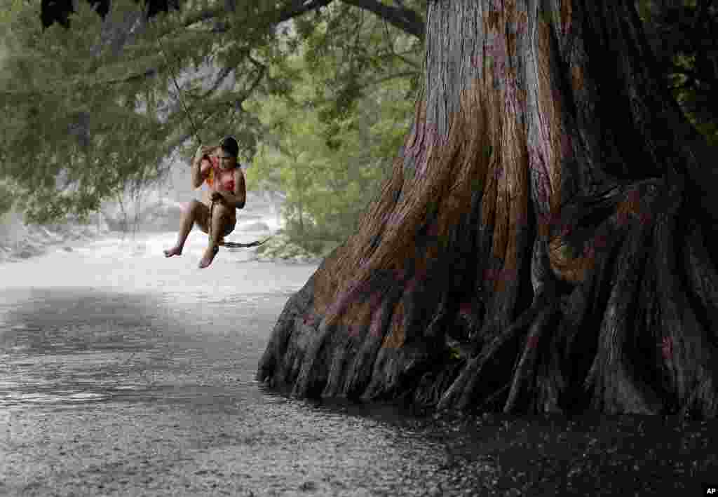 Anna Endsley enters the Guadalupe River via a rope swing in Gruene, Texas, USA, July 15, 2014.