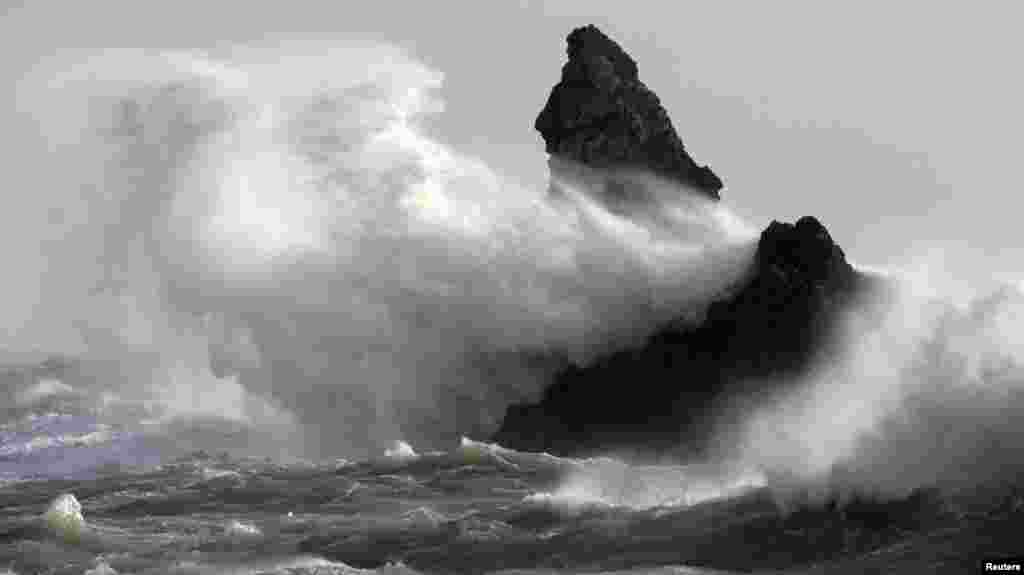 Deburan ombak menimpa Church Rock dalam terpaan angin yang kuat di Broad Haven, Wales. Peringatan banjir dikeluarkan kembali untuk wilayah England, Wales dan Scotlandia seiring dengan kembalinya angin kencang dan hujan lebat di Inggris.