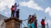 Mujeres levantan los brazos después de colocar una escultura sobre un monumento dedicado a los derechos de las mujeres titulado "Glorieta de las mujeres que luchan" antes del Día Internacional de la Mujer, en Ciudad de México, sábado, 5 de marzo de 2022.