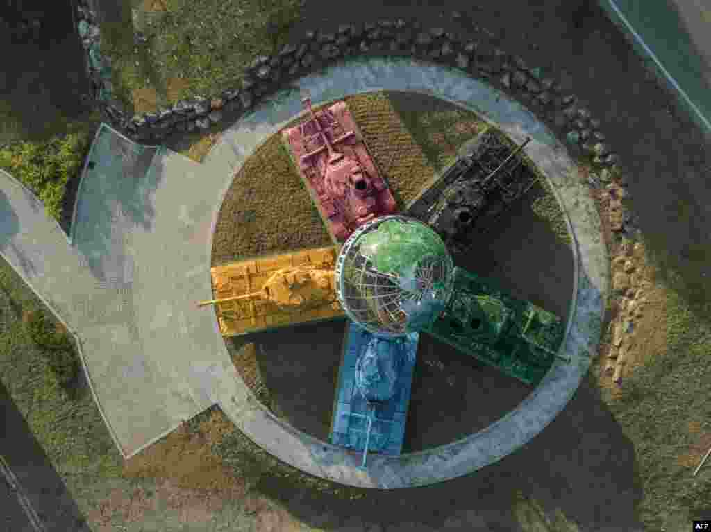 An aerial view of an art installation featuring Korean war-era tanks painted in different colors around a globe with a slogan reading: 'Peace All Around the World', at the Peace dam, north of Hwacheon near the Demilitarized Zone (DMZ) separating North and South Korea, May 21, 2017.