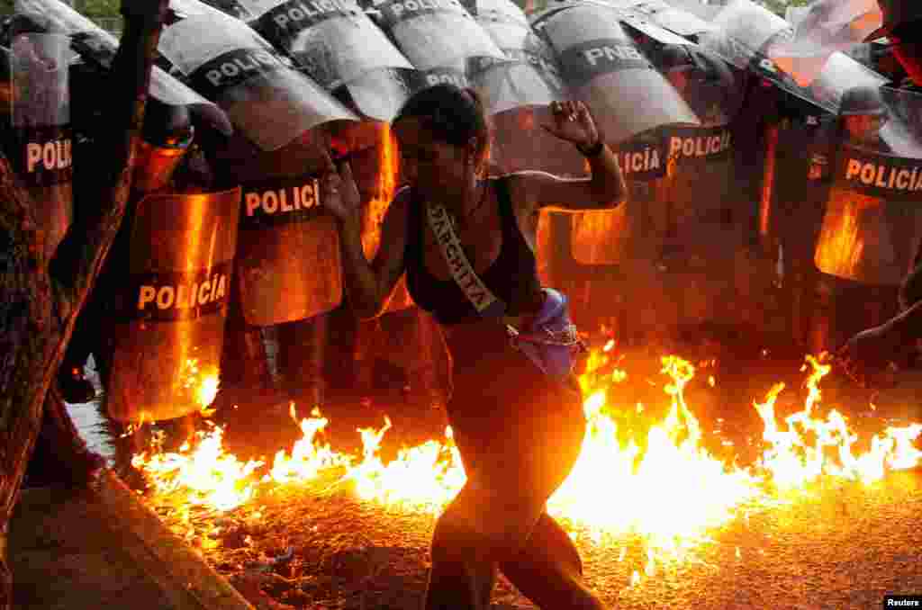A demonstrator reacts when Molotov cocktails hit the ground in front of security forces during protests against election results after Venezuela's President Nicolas Maduro and his opposition rival Edmundo Gonzalez claimed victory in Sunday's presidential election, in Puerto La Cruz, July 29, 2024. 