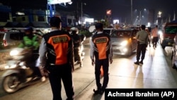 Para petugas Dishub dan polisi menjaga pos pemeriksaan di Cibitung, Bekasi, Jawa Barat, saat penerapan larangan mudik nasional untuk mencegah penyebaran pandemi COVID-19, Minggu, 9 Mei 2021. (Foto: Achmad Ibrahim/AP)