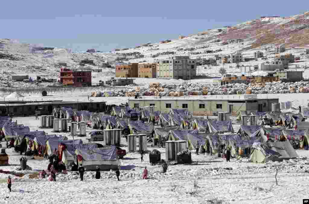 Para pengungsi Suriah berjalan keluar tenda mereka di kamp pengungsi di kota Arsal, perbatasan Lebanon dengan Suriah (15/12). (AP/Bilal Hussein)