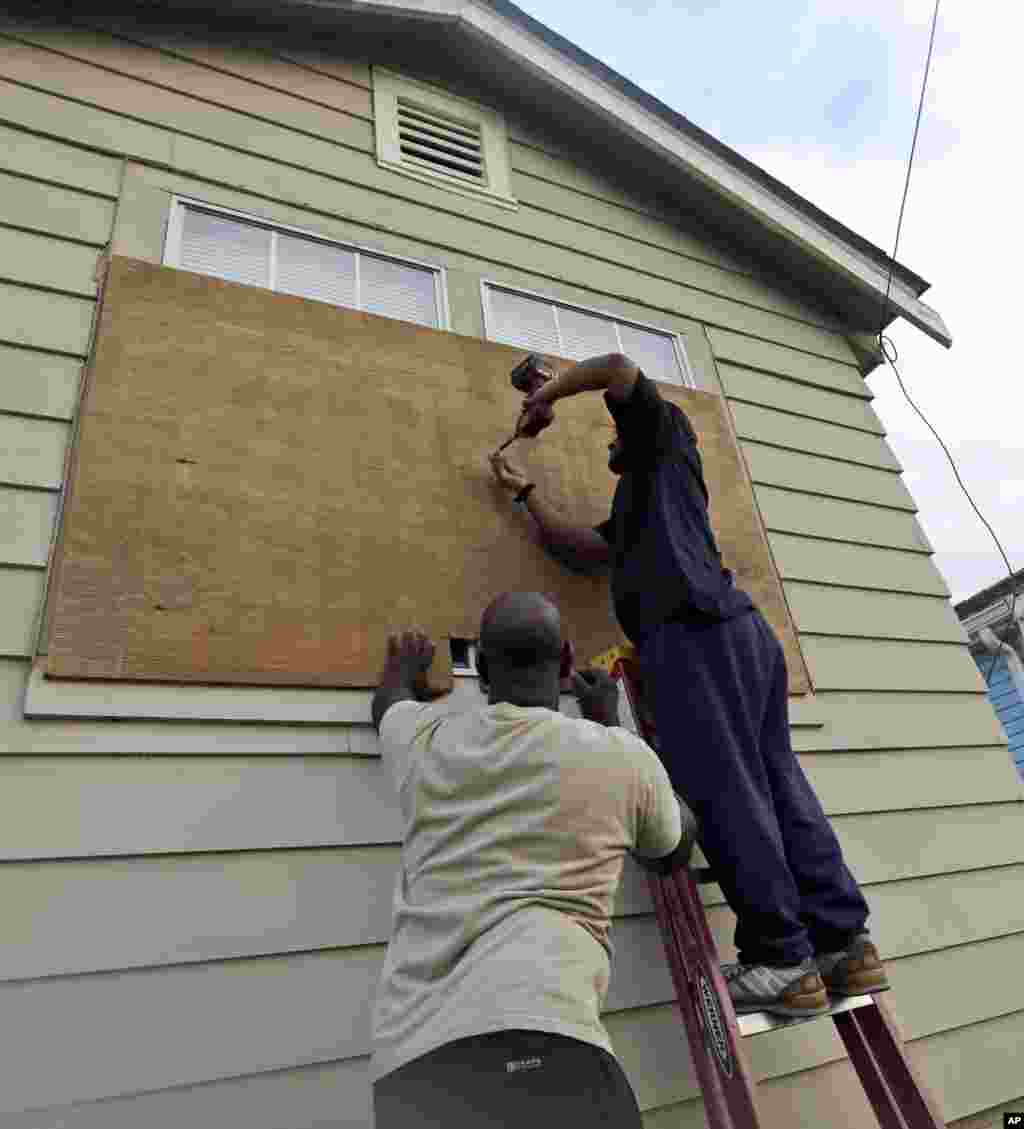 Stacey Davis, left, and his brother board up windows on their home before Tropical Storm Isaac hits Aug. 28, 2012, in New Orleans.