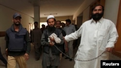 FILE - Police escort a man, identified as the Afghan Taliban's top military commander, Mullah Abdul Ghani Baradar.