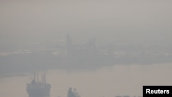 FILE - A cargo ship is seen through pollution along the Chao Phraya river in Bangkok, Thailand, Jan. 11, 2019.