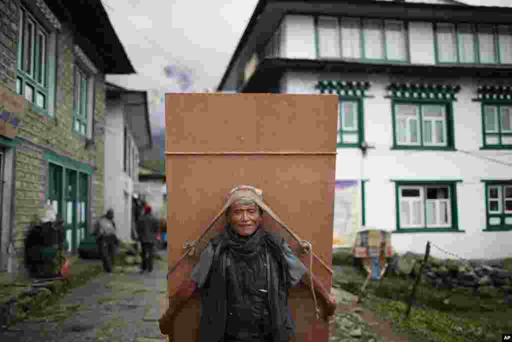 Seorang pekerja Nepal membawa plywood di kota Lukla, Nepal.