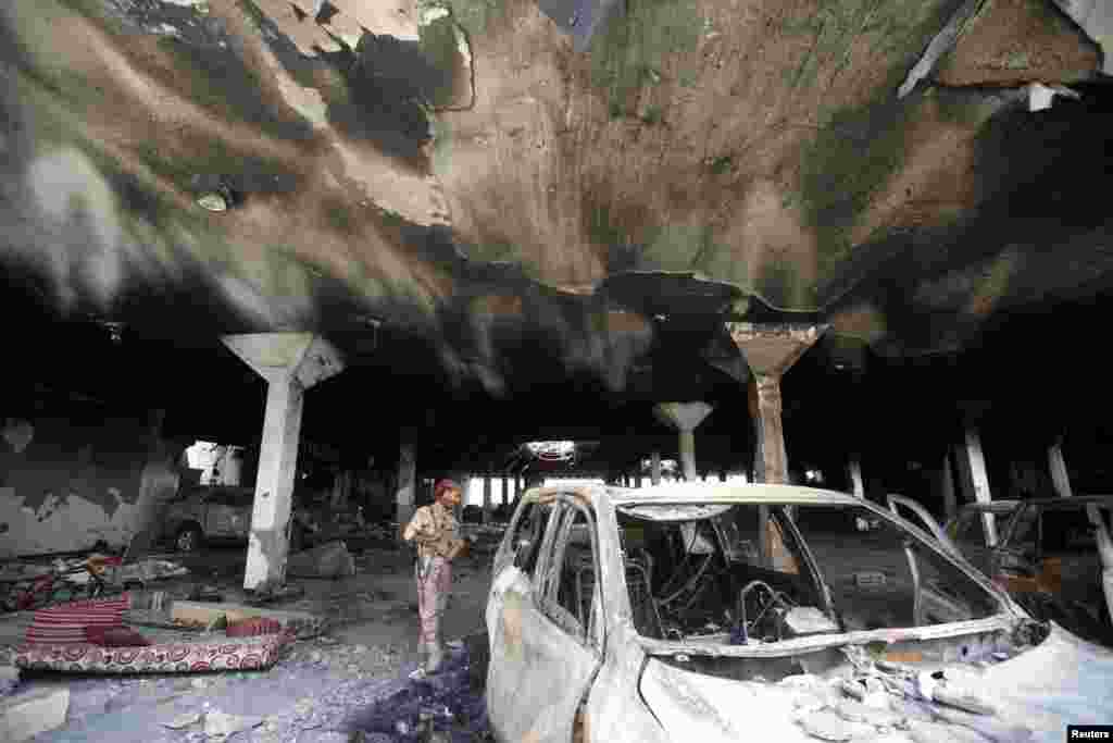 A security guard looks at a damaged car during a visit by human rights activists to a community hall in Sana'a, Yemen, that was struck by an airstrike during a funeral on Oct. 8.