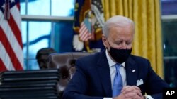 Le président Joe Biden fait une pause alors qu'il signe ses premiers décrets dans le bureau ovale de la Maison Blanche le mercredi 20 janvier 2021, à Washington. (Photo AP / Evan Vucci)