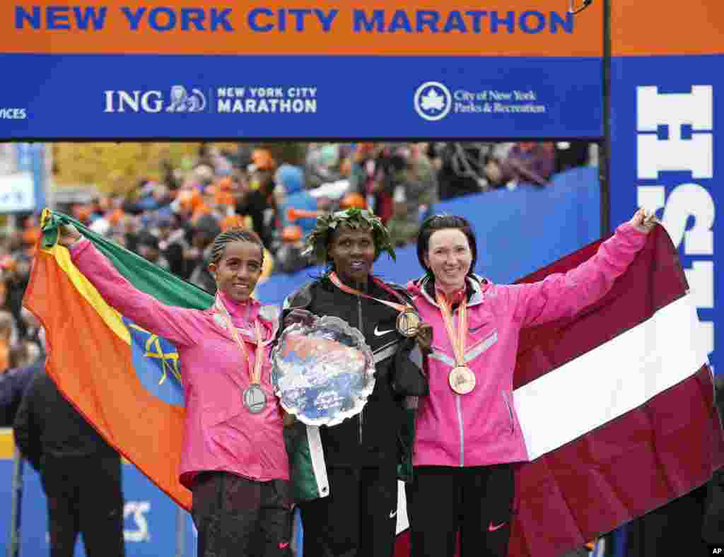 Women's winner Priscah Jeptoo of Kenya, center, second place finisher Buzunesh Deba of Ethiopia, left, and third place finisher Jelena Prokopcuka of Latvia pose with their medals after the New York City Marathon, Nov. 3, 2013.
