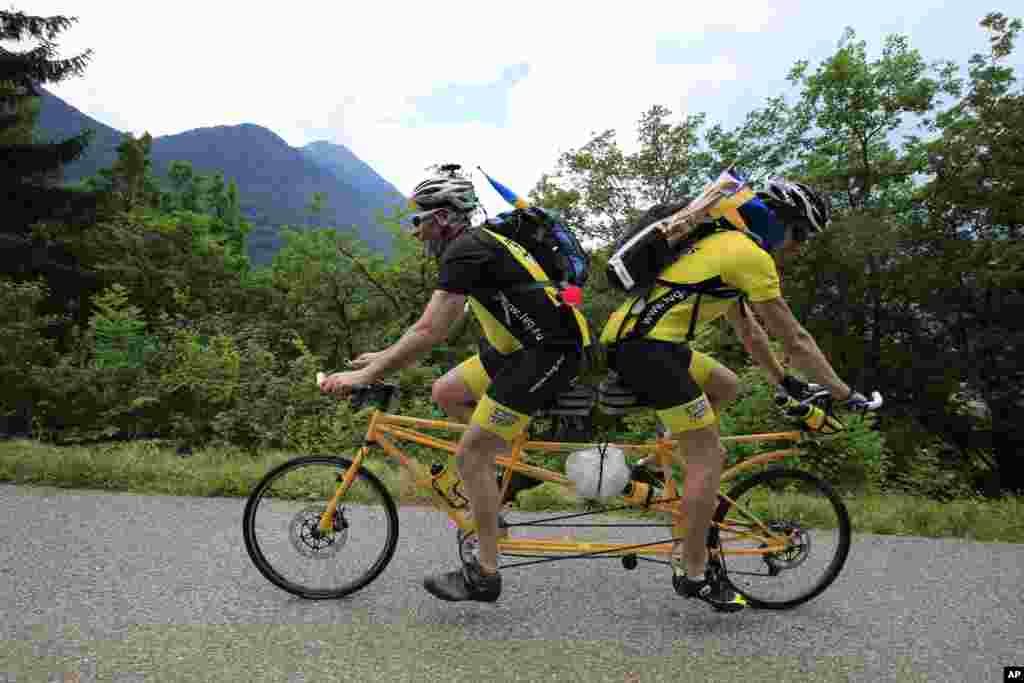 Ake Johansson dari Swedia (kiri), dan temannya mendaki lintasan L'Epine di atas sepeda tandem buatan sendiri dalam tahapan ke-19 Tour de France.