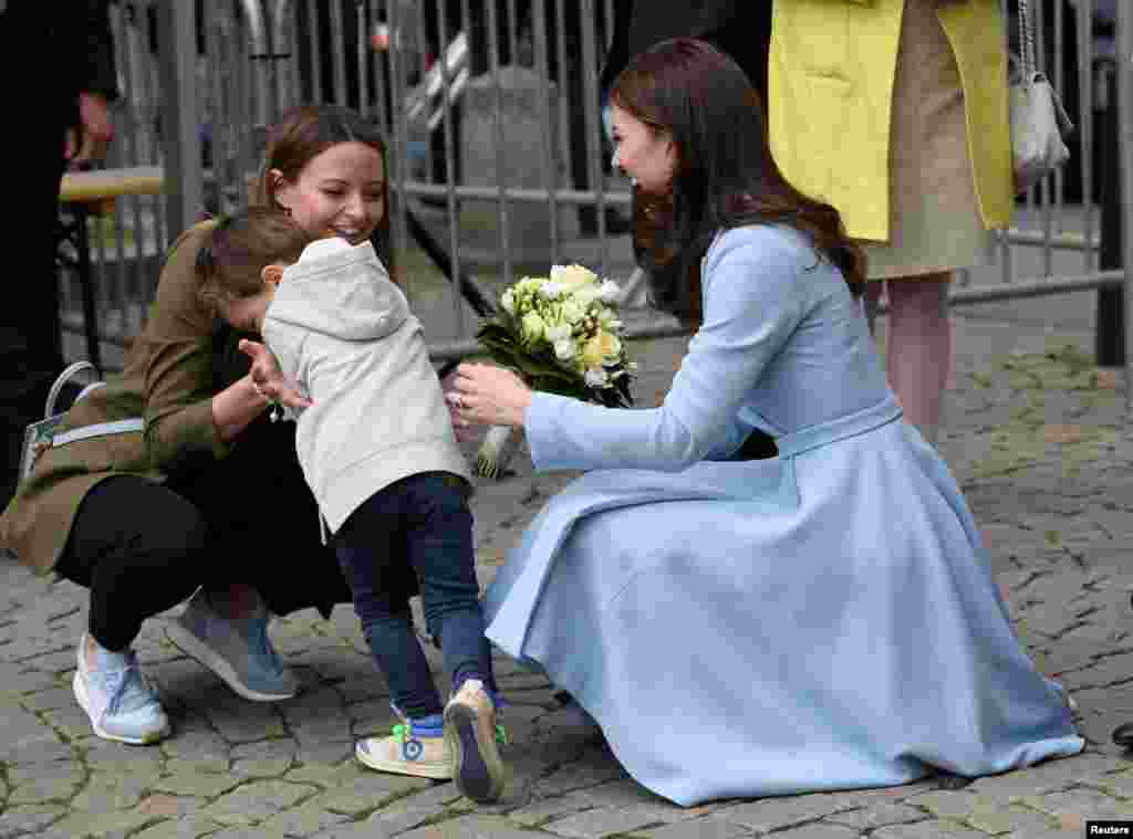Seorang anak laki-laki tersipu malu setelah memberikan bunga kepada Putri Inggris Catherine, di Luxembourg.