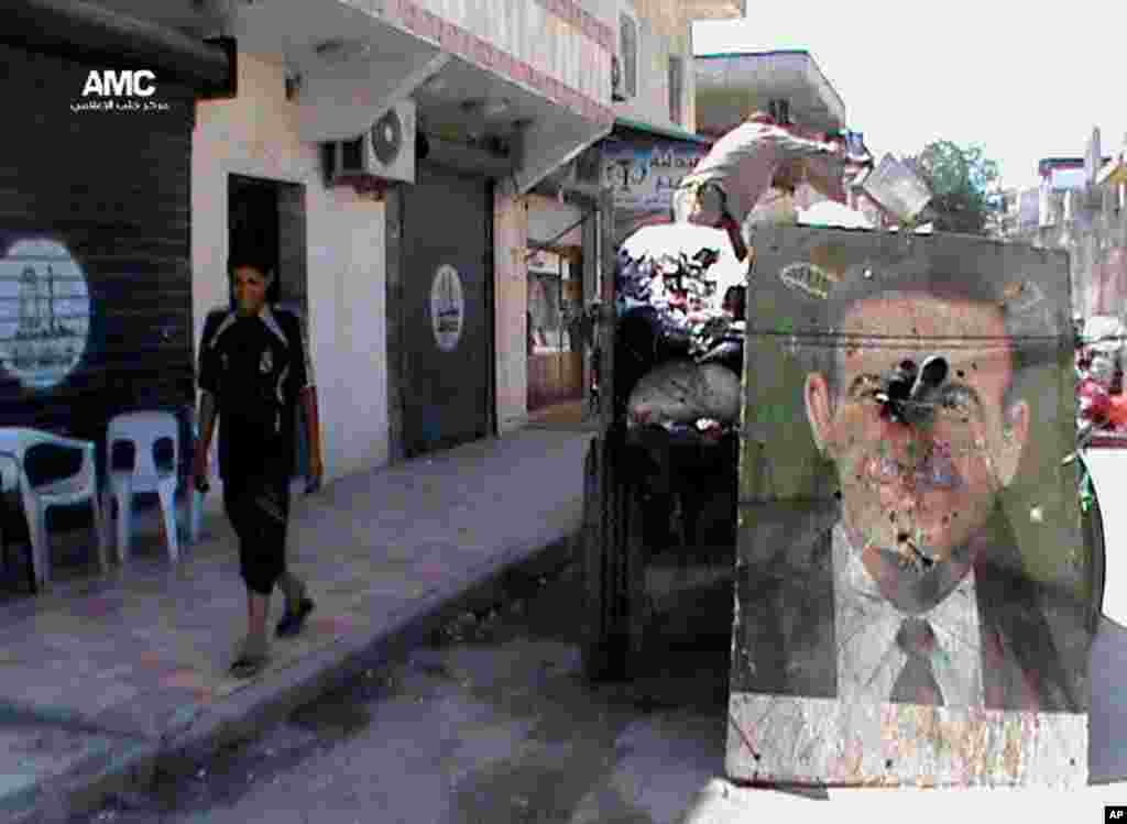 This citizen journalism image provided by Aleppo Media Center AMC shows a poster of late Syrian President Hafez Assad on a garbage truck, in Aleppo, Syria, June 6, 2013.