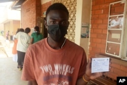 A Ugandan man holds a vaccination card that proves he has received the yellow fever vaccine, at Kiswa Health Center III in Kampala, Uganda Tuesday, April 2, 2024. (AP Photo)