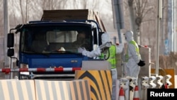 身穿防護服的警察在河北省通往北京的一個道路檢查站攔住一輛卡車。（資料照， 2021年1月12日
