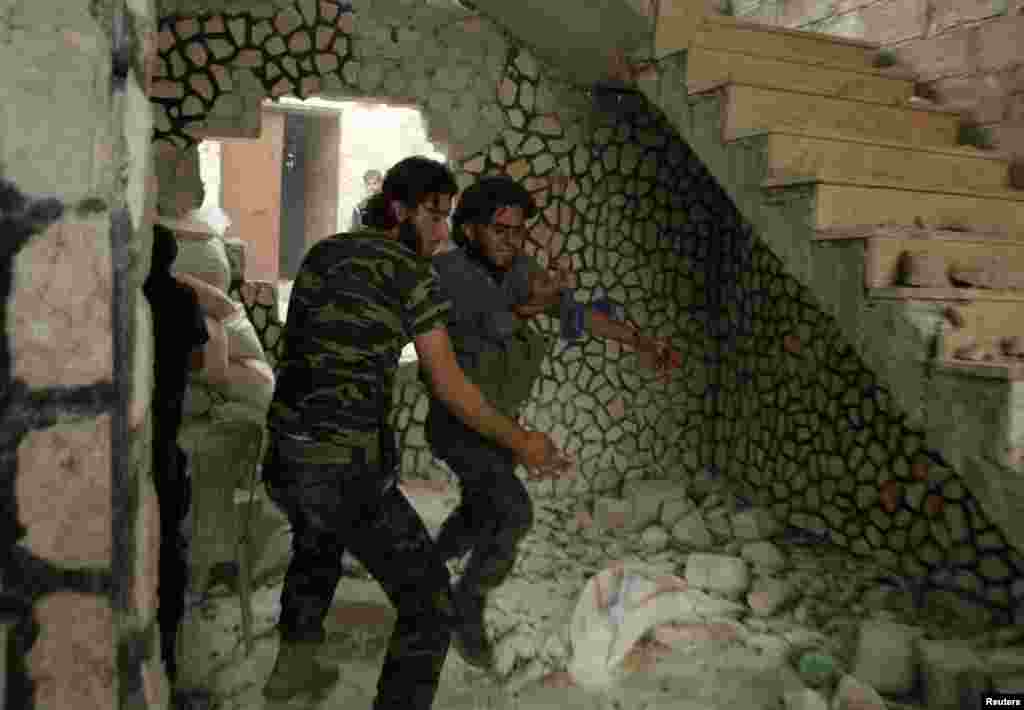 Seorang pejuang dari Tentara Pembebasan Suriah menolong rekannya yang terluka di distrik Al-Amariya, Aleppo, 8 Mei 2014. (REUTERS/Ammar Abdullah)