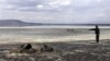 FILE - Kenya Wildlife Service warden Vincent Ongwae looks at the carcass of a buffalo that had died due to drought, on the shore of Lake Nakuru in Kenya, October 2009.
