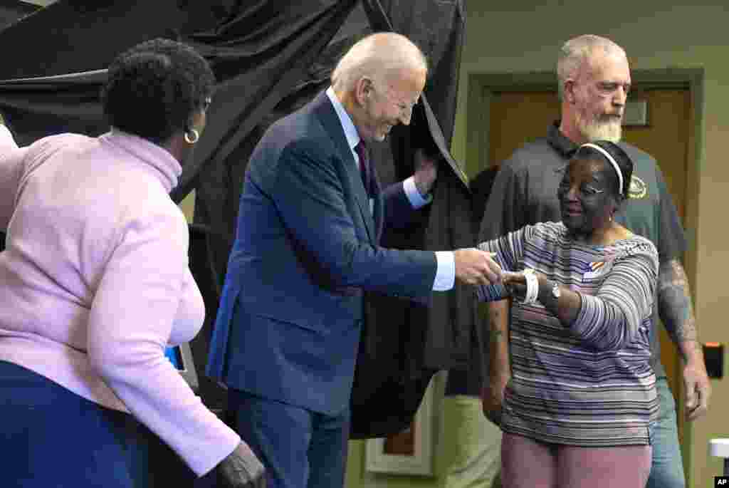 President Joe Biden is handed an "I Voted Early" sticker upon exiting the voting booth after casting his early-voting ballot for the 2024 general elections in New Castle, Delaware.