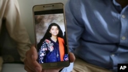 Abdul Aziz Sheikh, center, father of Sabika Sheikh, a victim of a shooting at a Texas high school, shows a picture of his daughter in Karachi, Pakistan, May 19, 2018.