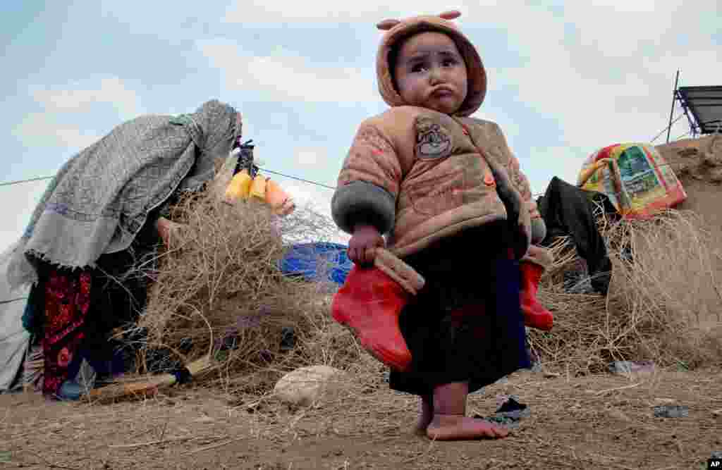 Seorang anak pengungsi Afghanistan membawa sepatu bootsnya di sebuah kamp pengungsi di kota Mazar-e Sharif, utara Kabul. 