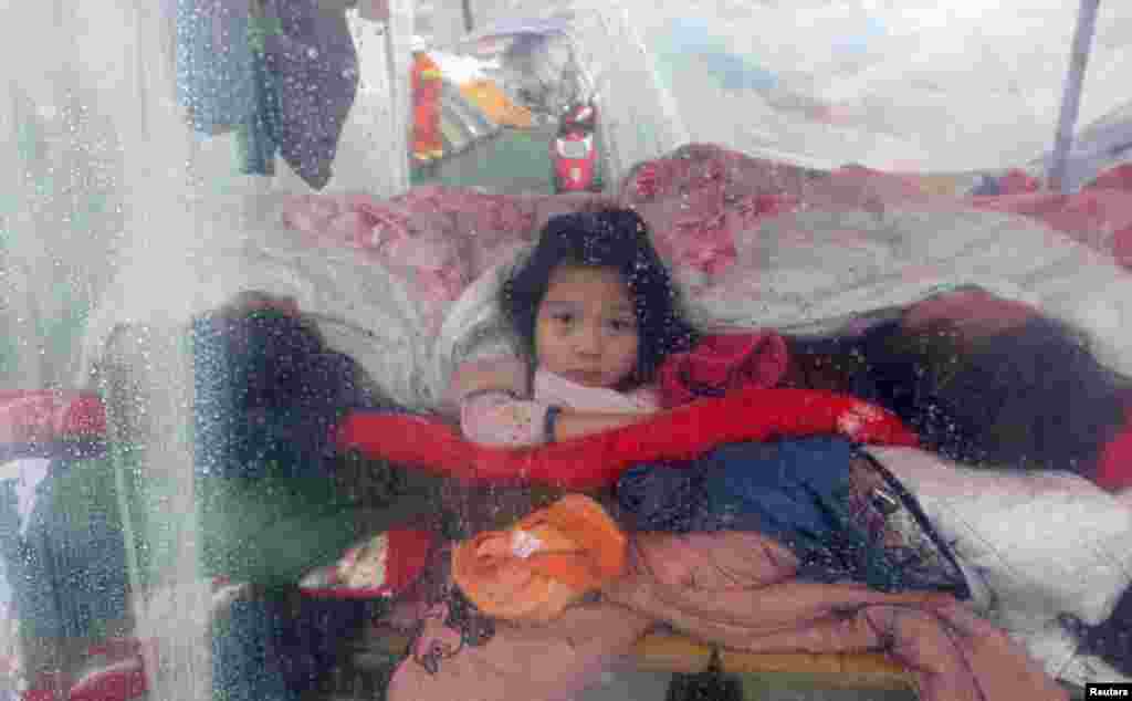Seorang gadis kecil, yang tinggal bersama keluarganya di sebuah tenda darurat, melihat hujan yang turundi luar tenda, pasca gempa di kota Lingguan, provinsi Sichuan, China.