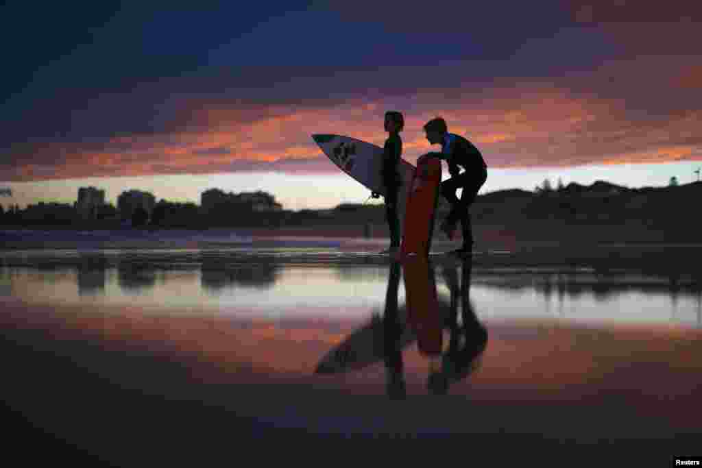 Young surfers, nicknamed 'grommets' in local surfing parlance, wait for their friends to finish a post-sunset session on the waves off Wanda Beach in Sydney, Australia.