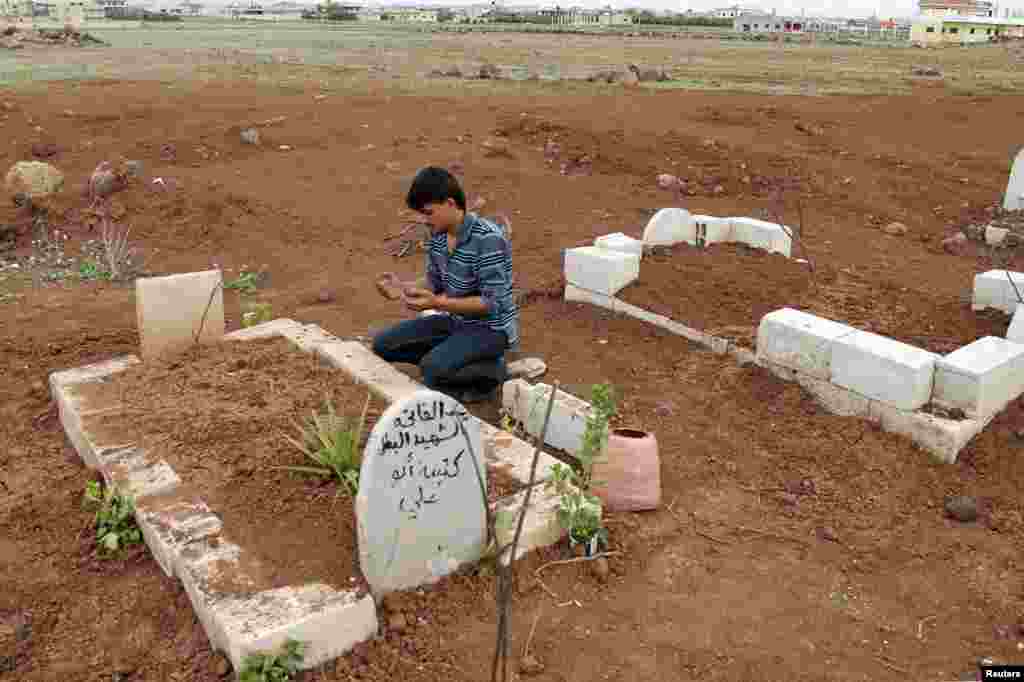 A man prays at the grave of a Free Syrian Army fighter at a cemetery at al-Karak al-Sharqi in Deraa, Syria, March 30, 2013.