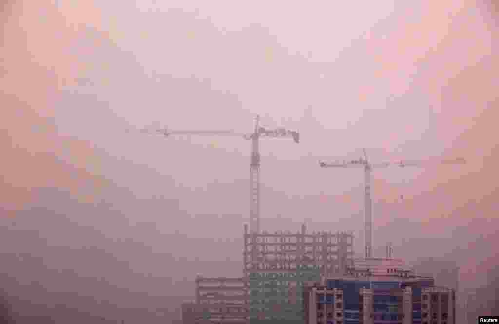 2012年4月18日，透过浓雾依稀可见北京中心地带一座仍在施工的居民楼旁边的吊车。多年里，北京是个大工地，造就高楼林立，也造成大量建筑粉尘。