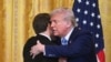 Дональд Трамп и Эммануэль Макрон завершают пресс-конференцию в Белом доме дружескими объятиями. 24 февраля 2025 года. (Photo by ROBERTO SCHMIDT / AFP).