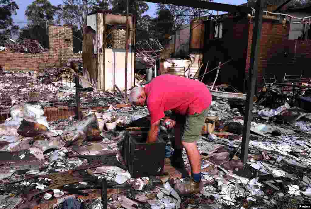 Local resident Alan Seaman looks inside a safe in the remains of his home that was destroyed by a fire in the Blue Mountains suburb of Winmalee, west of Sydney, Oct. 21, 2013.