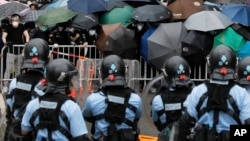 2019年6月12日在香港立法會附近，帶有防暴裝備的警察同打著雨傘的示威者對峙。