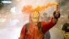 A protester wearing a mask holds a firework during a rally outside the headquarters of the Siam Commercial Bank, a publicly-held company in which the Thai king is the biggest shareholder, in Bangkok Thailand, Nov. 25, 2020.