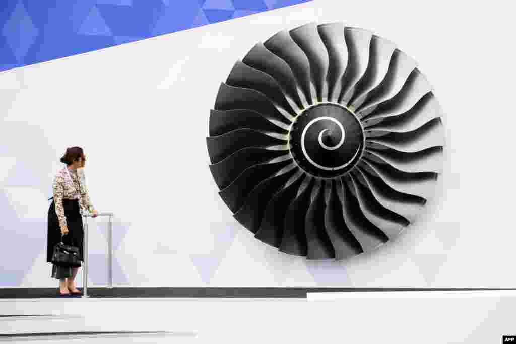 A woman stands near a model of a Rolls Royce Trent engine at the Farnborough Air Show in Hampshire, southern England.