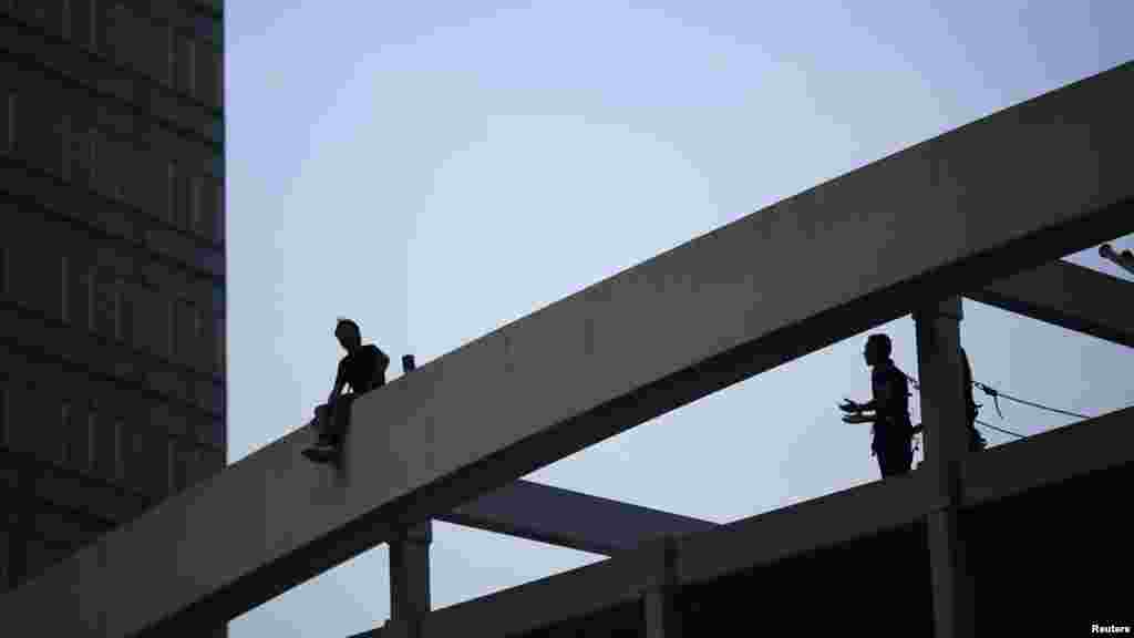 Seorang demonstran pro-pemerintah (kiri) mengancam akan melompat dari jembatan kecuali pembatas-pembatas jalan yang dipasang oleh para demonstran pro-demokrasi dipindahkan dari depan gedung-gedung pemerintahan di Hong Kong (5/10). (Reuters/Carlos Barria)