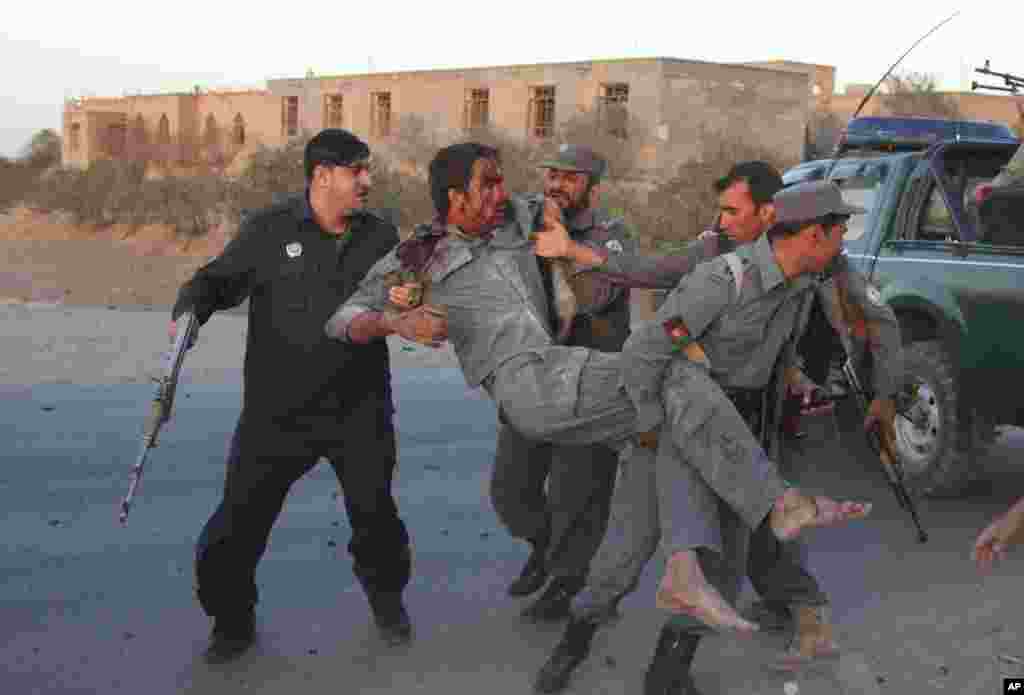 Afghan security personnel assist an injured police after a suicide car bombing and a gunfight near the U.S. consulate in Herat, Afghanistan, Sept. 13, 2013.