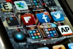 FILE - An iPhone with Twitter, Facebook and other apps, May 21, 2013. U.S. internet companies are taking a harder look at their policies that have promoted free expression around the world.