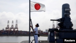 一名水手在日本加贺号直升机航母上升起日本国旗。（2018年9月30日）
