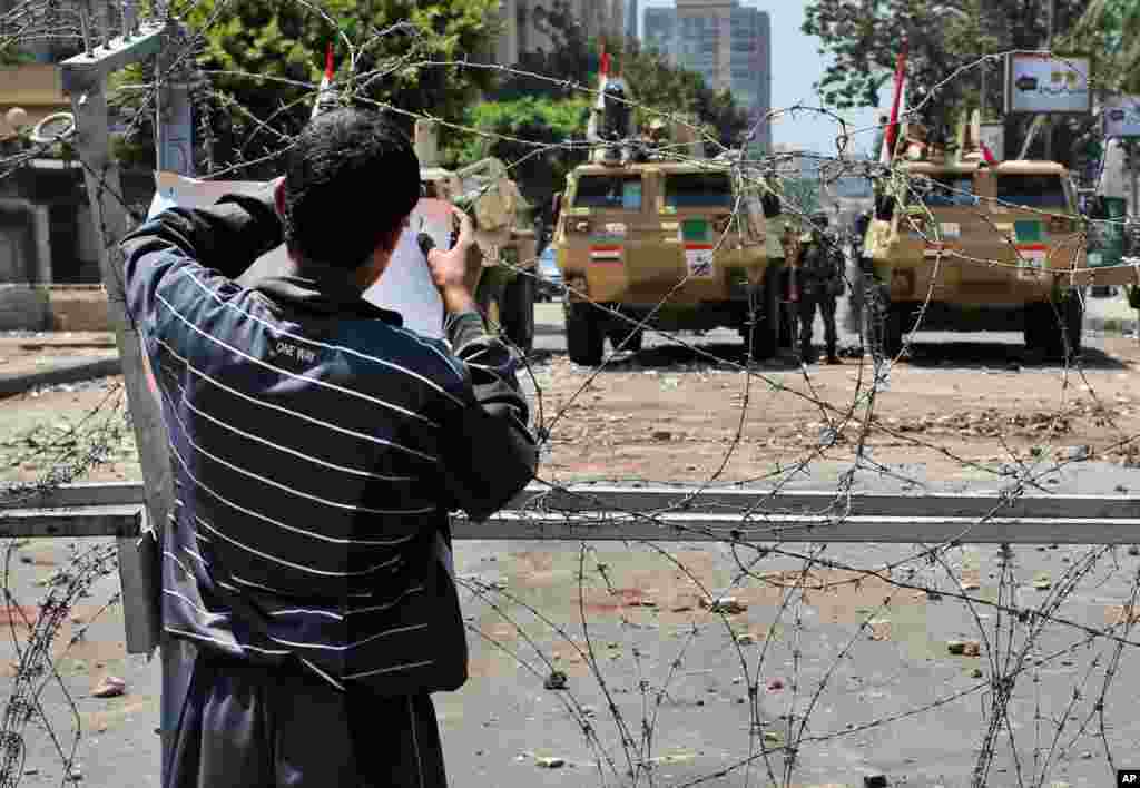 Seorang pendukung Mohamed Morsi menempelkan sebuah poster di jalan yang diblokade yang menyambung dengan gedung militer Republican Guard di Kairo, Mesir (15/7). (AP/Hussein Malla)