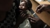 A mother holds her baby as she receives a new malaria vaccine at the Walter Reed Project Research Center in Kenya, October 30, 2009. 