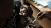 A mother holds her baby as she receives a new malaria vaccine at the Walter Reed Project Research Center in Kenya, October 30, 2009. 