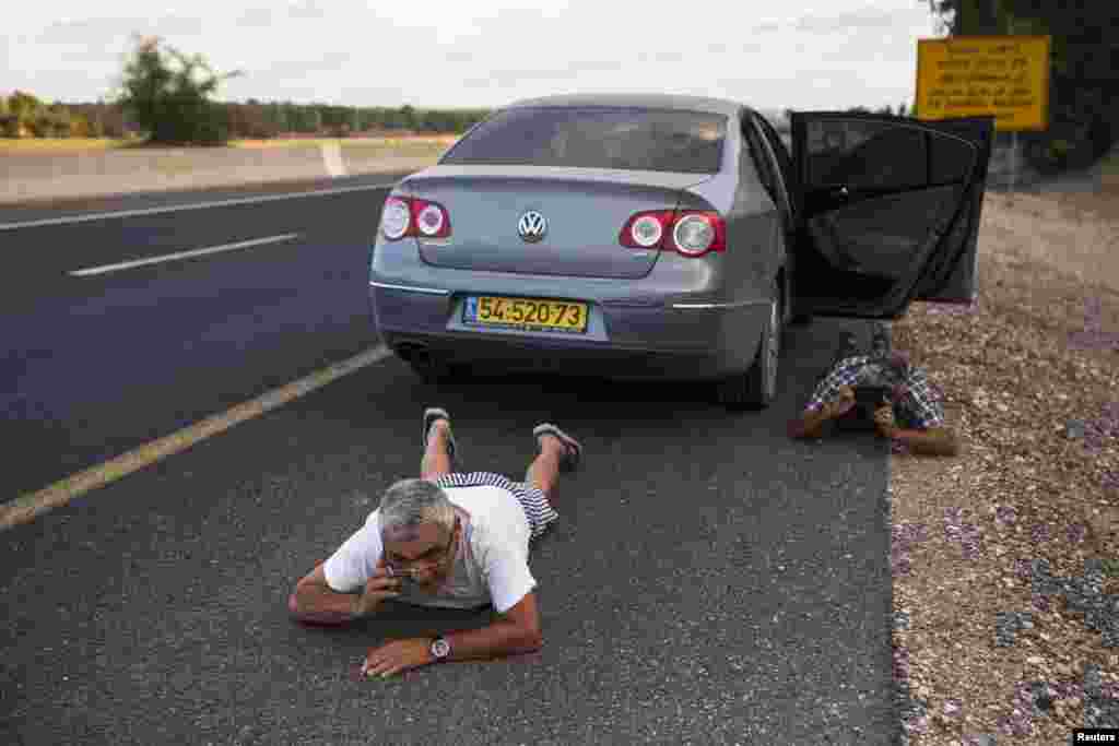 Seorang warga Israel berlindung di sisi jalan ketika suara sirene memperingatkan adanya roket yang sedang menuju ke arahnya, di luar utara Jalur Gaza, 15 Juli 2014.
