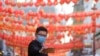 A man wears a mask as he takes a photograph in China Town in London, Feb. 7, 2020. 