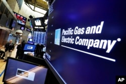 FILE - The logo for Pacific Gas & Electric Co. appears above a trading post on the floor of the New York Stock Exchange, Jan. 14, 2019.